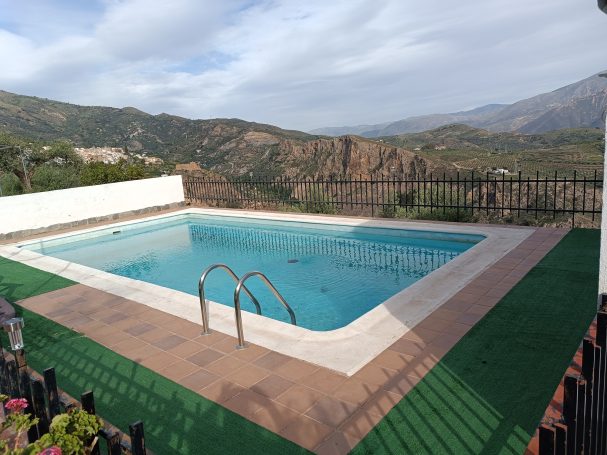Piscina al aire libre rodeada de montañas y paisaje natural.