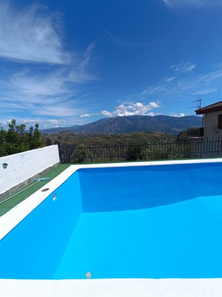 Piscina azul en un paisaje montañoso bajo un cielo despejado.