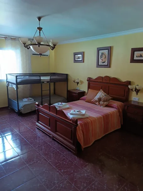 Habitación con cama doble, litera, muebles de madera y paredes amarillas.