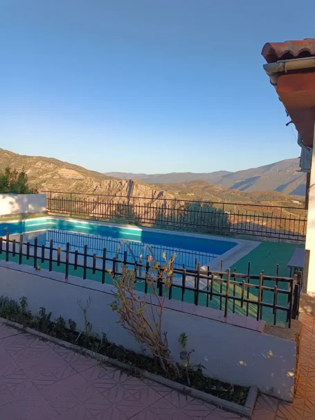 Piscina azul en un paisaje montañoso bajo un cielo despejado.