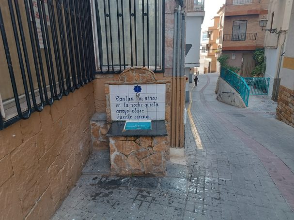 Fuente de agua con un cartel informativo en una calle residencial.