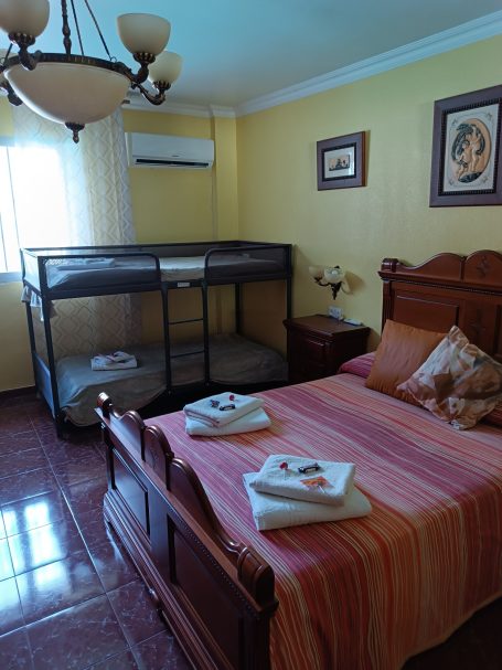 Habitación con cama, cuna, lámpara y decoración en tonos cálidos.