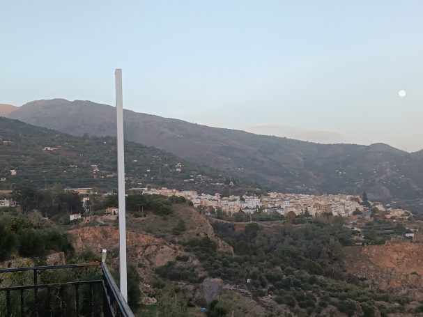 Vista de un paisaje montañoso al atardecer con un pueblo en el valle.