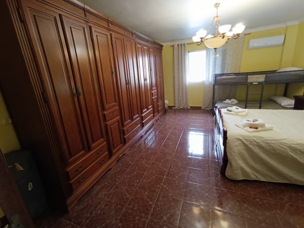 Habitación espaciosa con armario de madera, cama y suelo de baldosas brillantes.