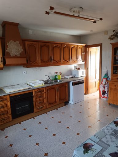 Cocina con muebles de madera, estufa, nevera y suelo de baldosas de colores.