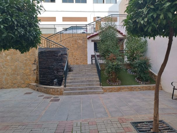 Jardín con escaleras, fuente y árboles, en un ambiente tranquilo y bien cuidado.