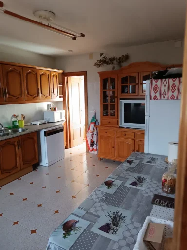 Cocina con muebles de madera, mesa blanca y detalles decorativos en la pared.