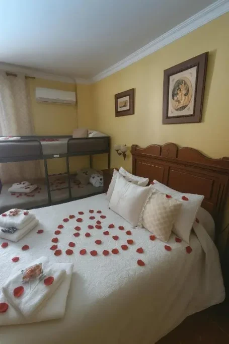 Cama con pétalos de rosa sobre las sábanas y toallas en una habitación decorada.
