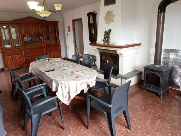 Comedor con mesa y sillas, chimenea, y decoraciones de madera en un ambiente acogedor.