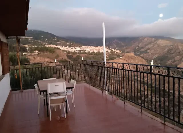 Paisaje montañoso con niebla y un cielo parcialmente nublado, luna visible. Vistas del Cortijo