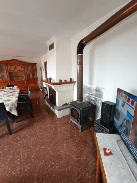 Sala de estar con mesa, chimenea, estufa y televisor en un ambiente acogedor.