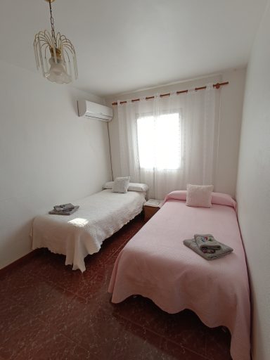 Habitación con dos camas individuales y luz natural, decorada en tonos claros.