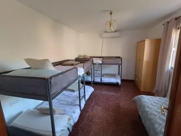 Habitación con una cama individual y una litera en un ambiente iluminado y ordenado.