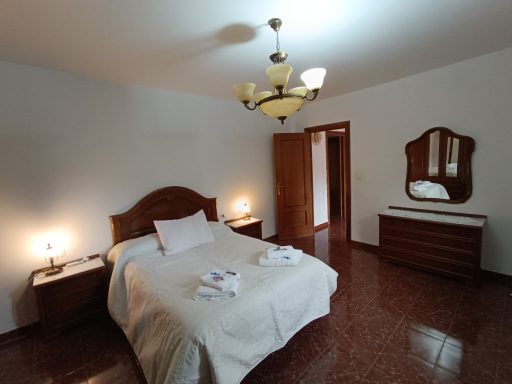 Habitación luminoso con cama matrimonial, mesitas y cómodas de madera.