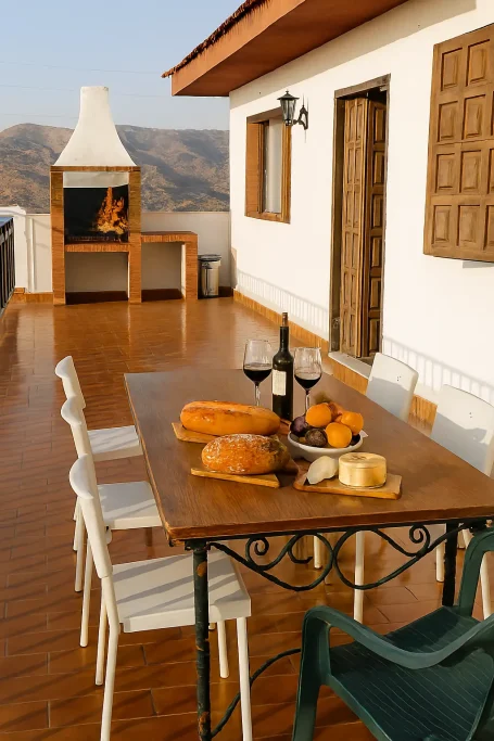 Mesa con comida y vino en una terraza con vistas a un paisaje montañoso.