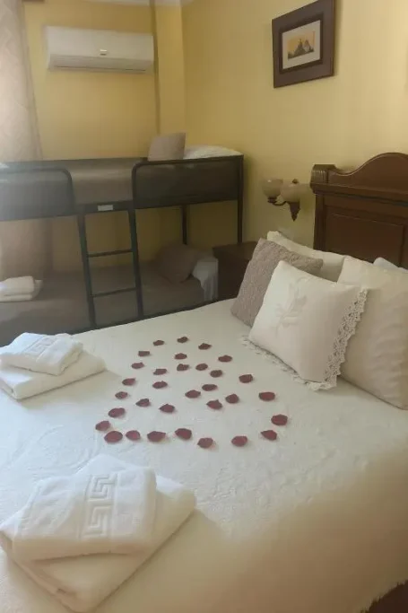 Habitación amarilla con cama, mesita de noche y armario, iluminada por un candelabro.