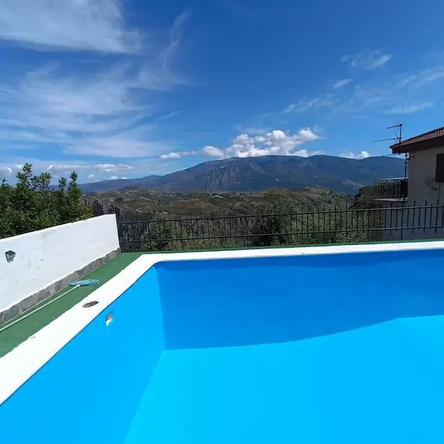Piscina privada azul con vistas panorámicas a las montañas de Sierra Nevada en Lanjarón.