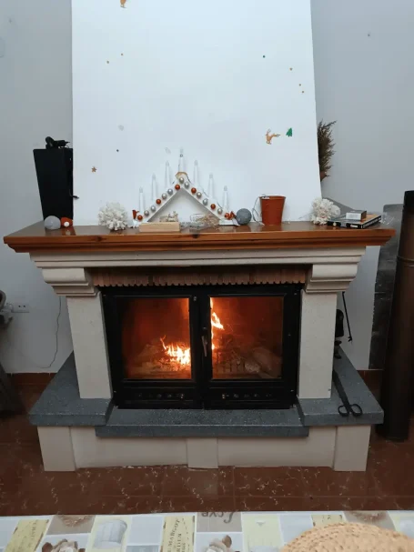 Chimenea encendida con leña y decoración sencilla en la parte superior.