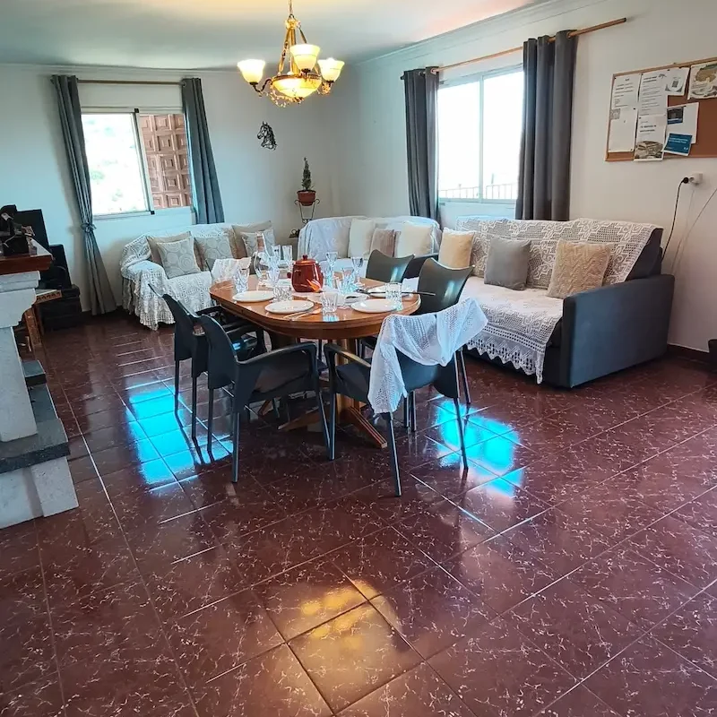 Salón para reuniones Sala de estar amplia con mesa, sillas, sofá y chimenea, decorada en tonos neutros.