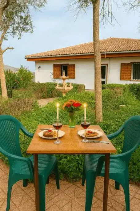 Mesa preparada para una cena romántica al aire libre, con flores y velas.