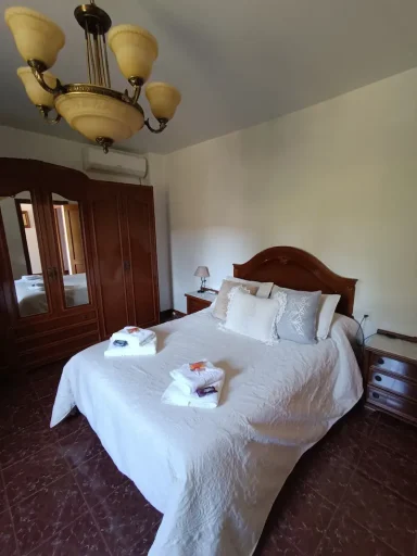 Habitación luminosa con cama doble, armario, lámparas y cortinas grises.