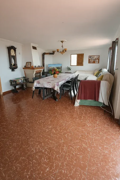 Sala de estar amplia con mesas, sillas y decoración sencilla en tonos claros.