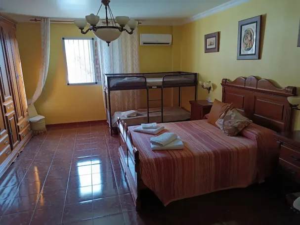 Habitación espaciosa con armario de madera, cama y suelo de baldosas brillantes.