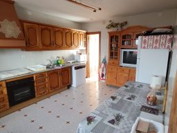 Cocina luminosa con muebles de madera, electrodomésticos y mesa en el centro.