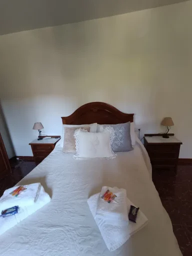 Cama matrimonial con sábanas blancas y lámparas de mesita a los lados.