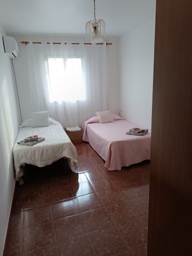 Habitación con dos camas individuales y luz natural, decorada con ropa de cama sencilla.