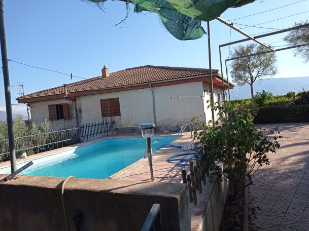 Casa con piscina al aire libre, jardines y vistas despejadas.